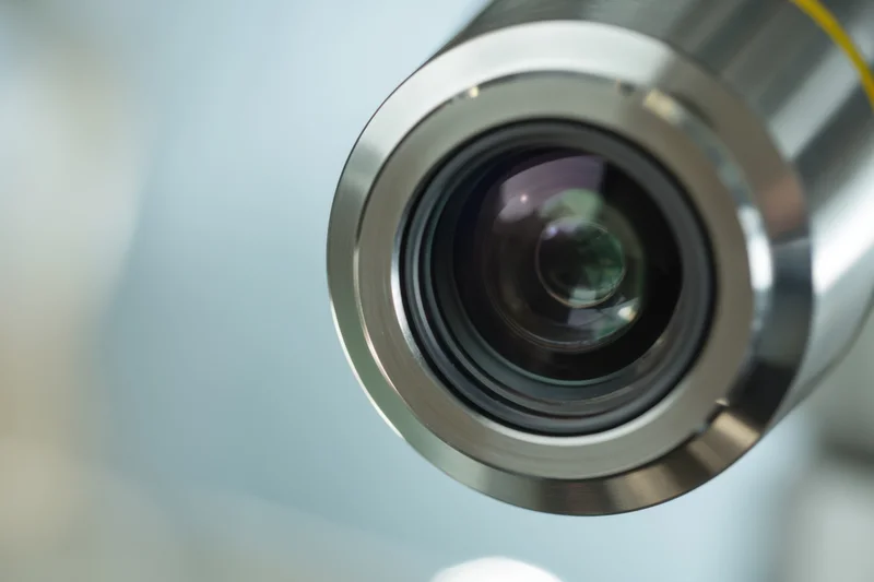Close-up of a microscope lens showing its glass and metallic housing with a blurred background