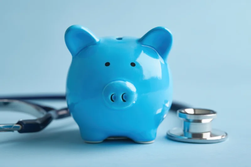 Blue piggy bank with stethoscope on light blue surface