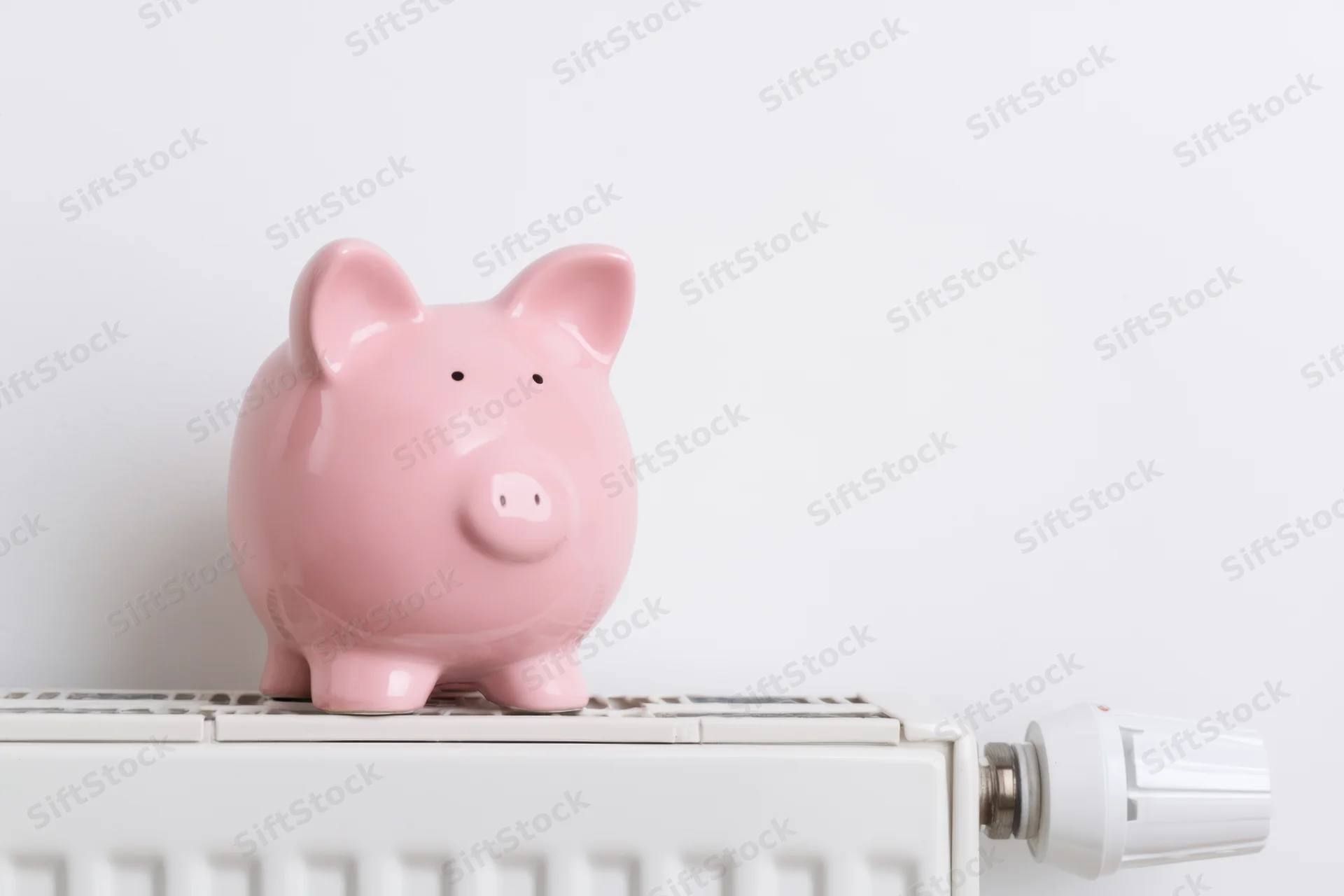 Pink ceramic piggy bank sitting on top of white radiator in home interior