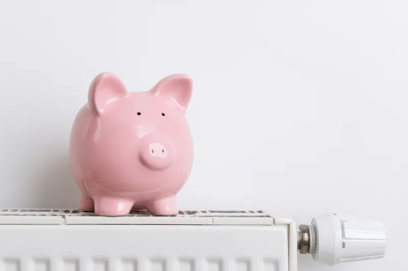 Pink ceramic piggy bank sitting on top of white radiator in home interior