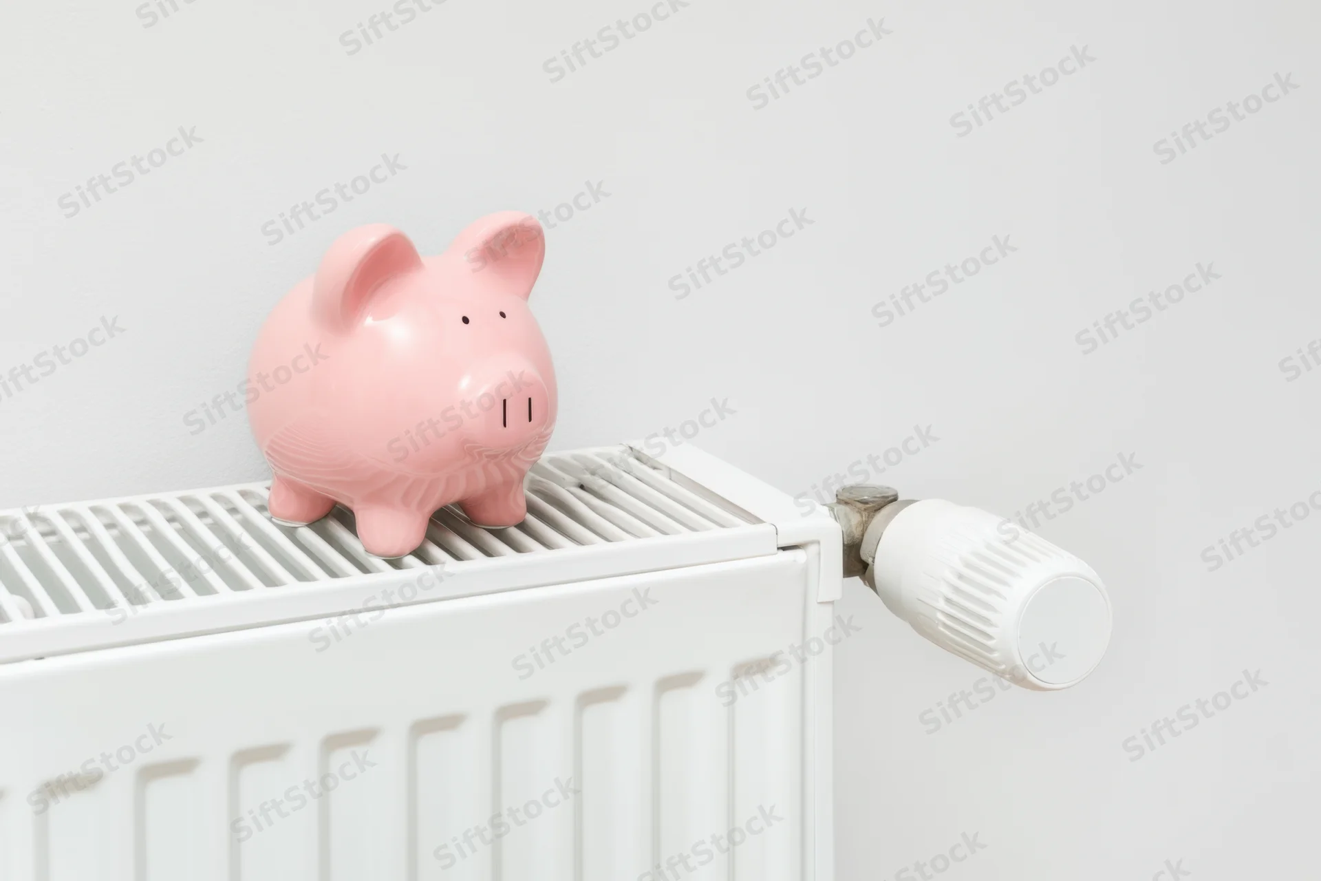 Pink piggy bank sitting on top of white radiator in home interior