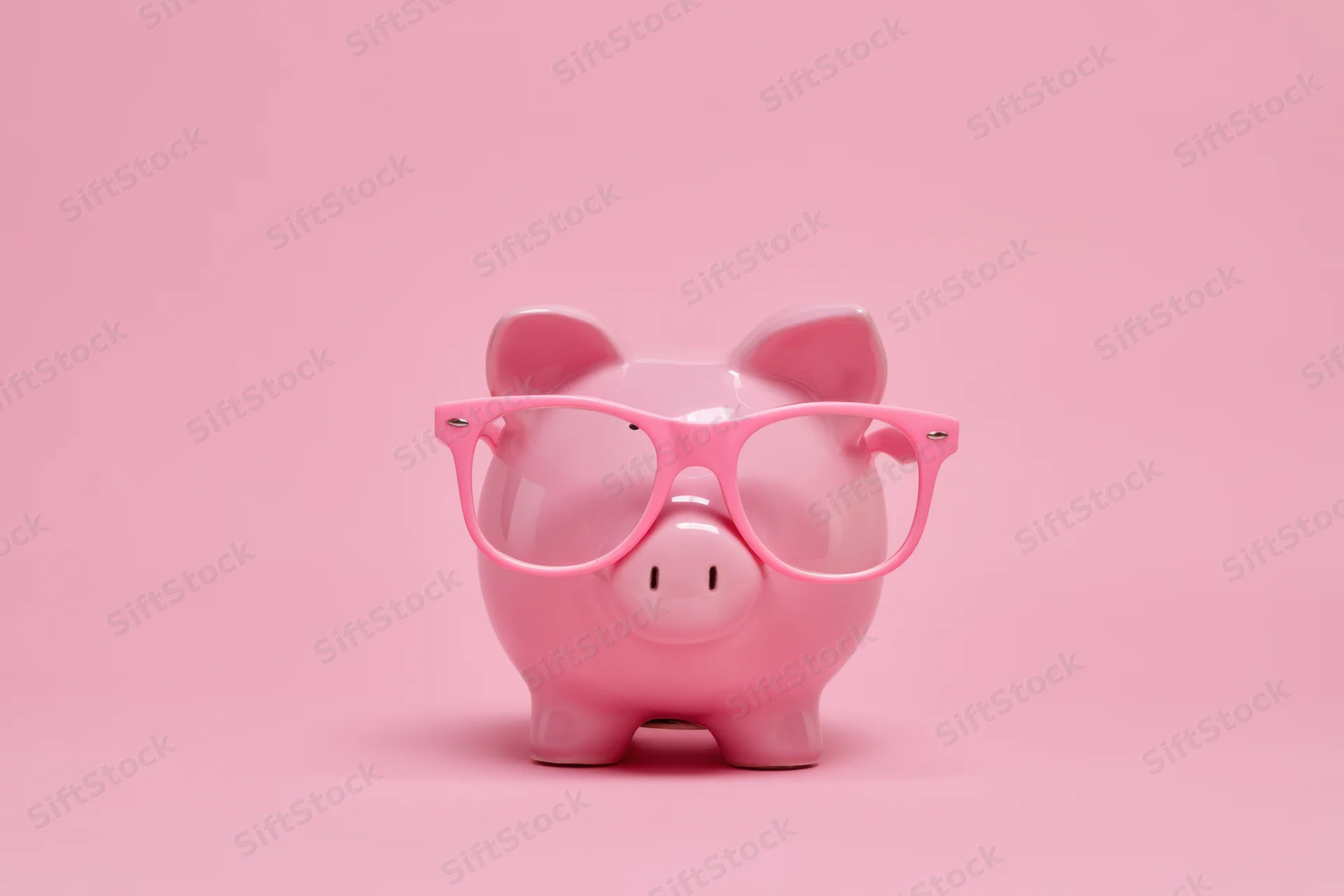 Pink piggy bank wearing oversized pink glasses on a pink background