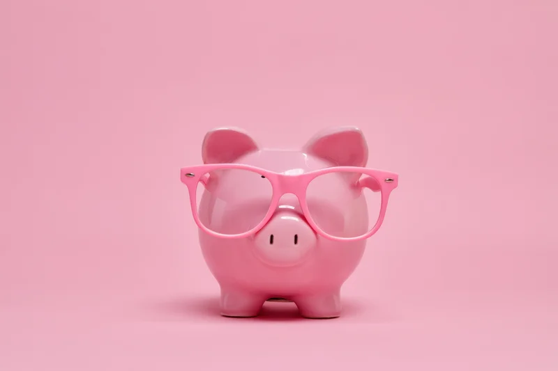 Pink piggy bank wearing oversized pink glasses on a pink background