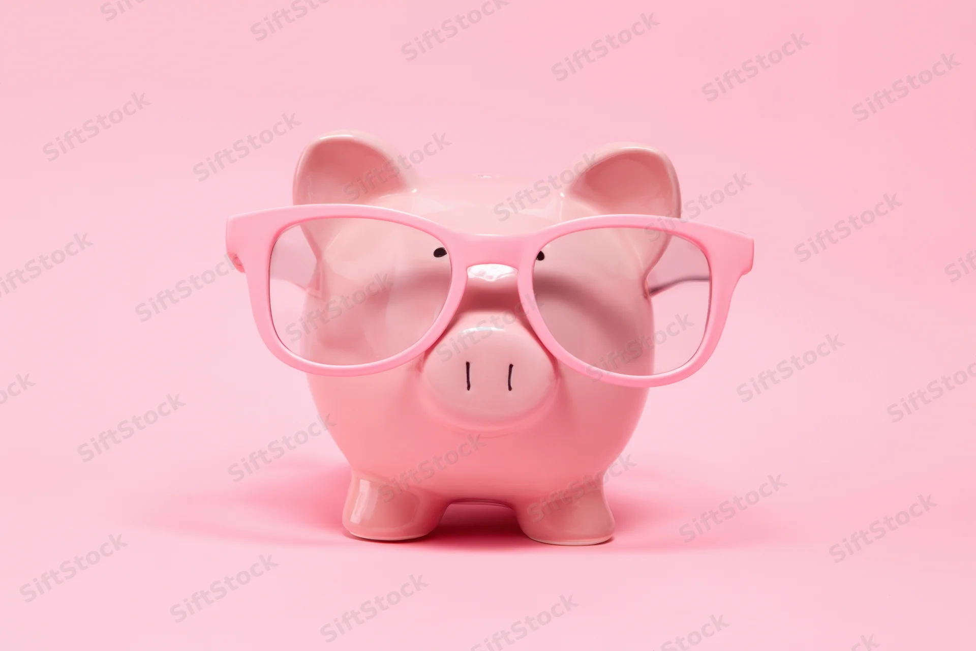 Pink piggy bank wearing oversized pink glasses on a pink background