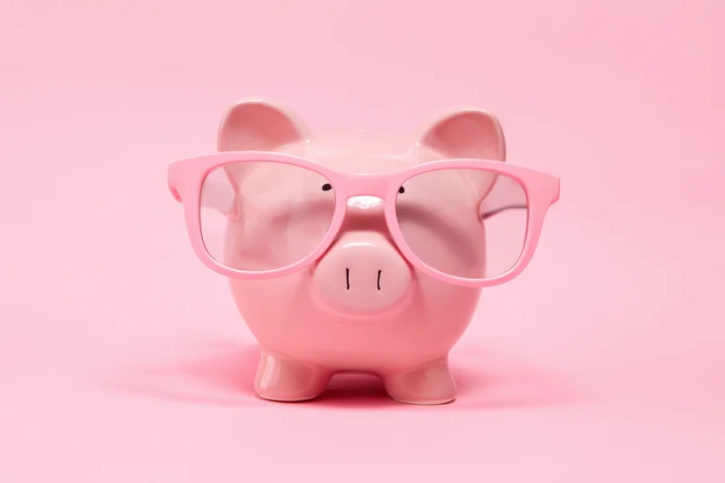 Pink piggy bank wearing oversized pink glasses on a pink background