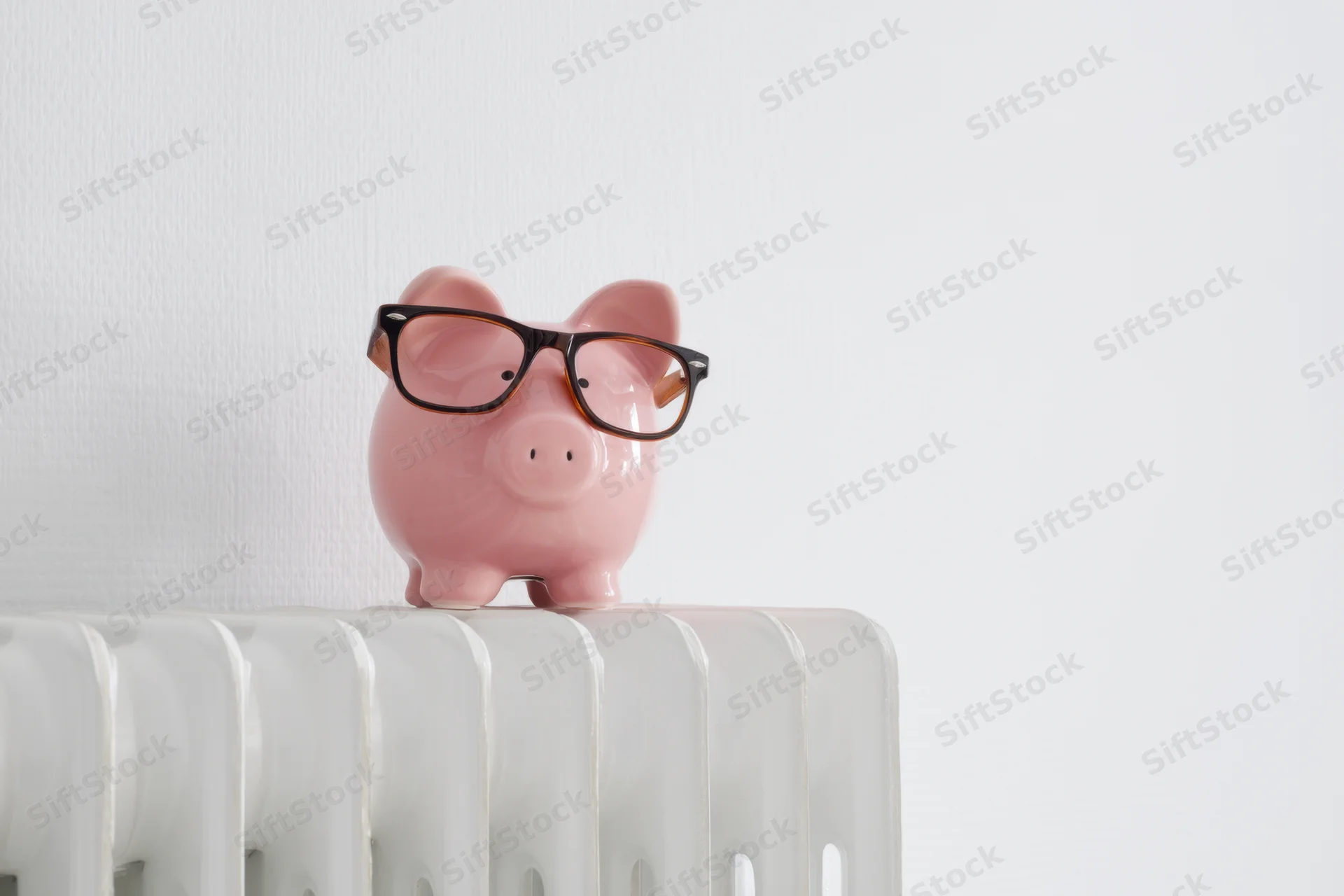 Pink piggy bank wearing glasses perched on white radiator in minimalist interior
