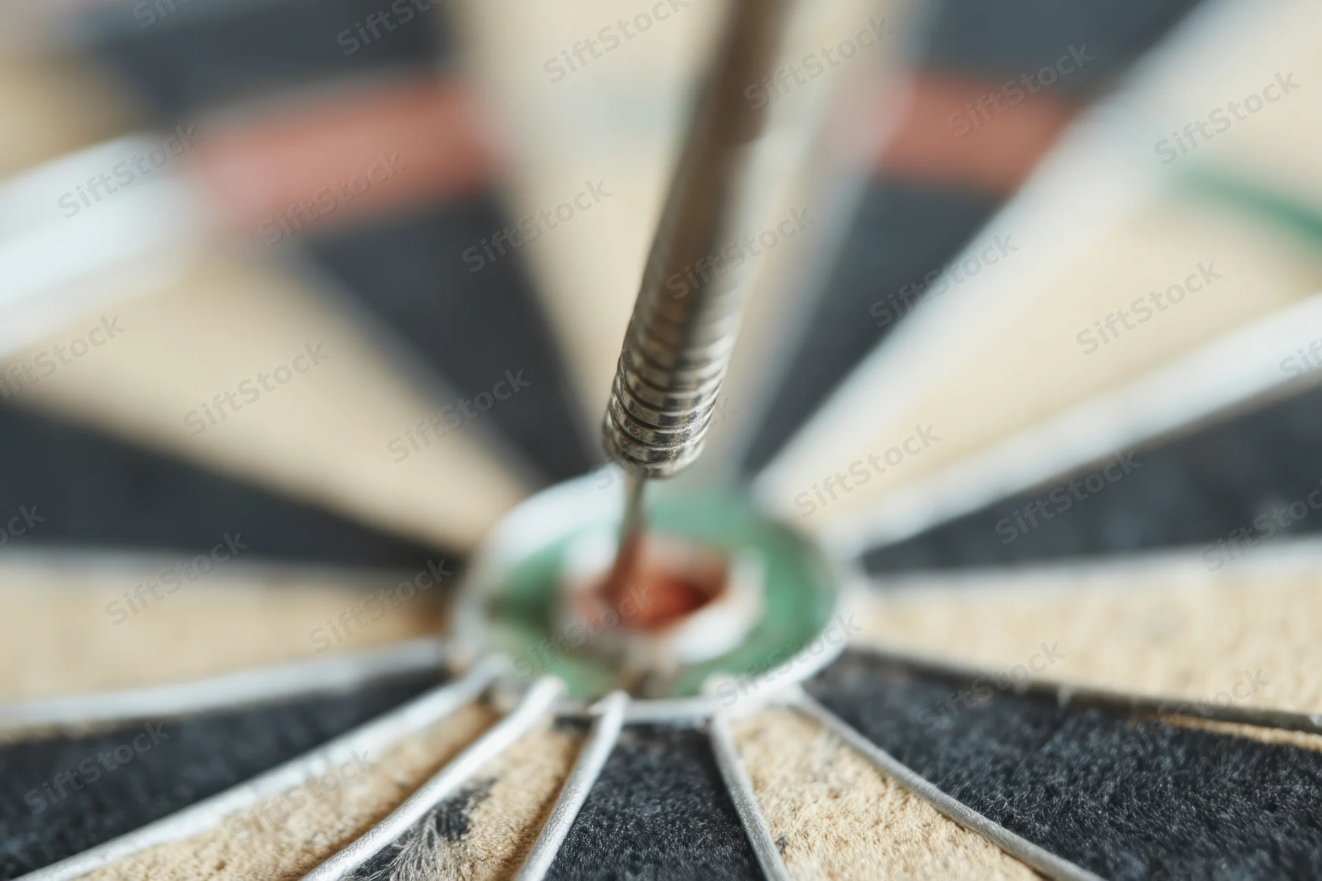 Dart lodged in the bullseye of a dartboard, close-up view showing concentric rings and scoring segments