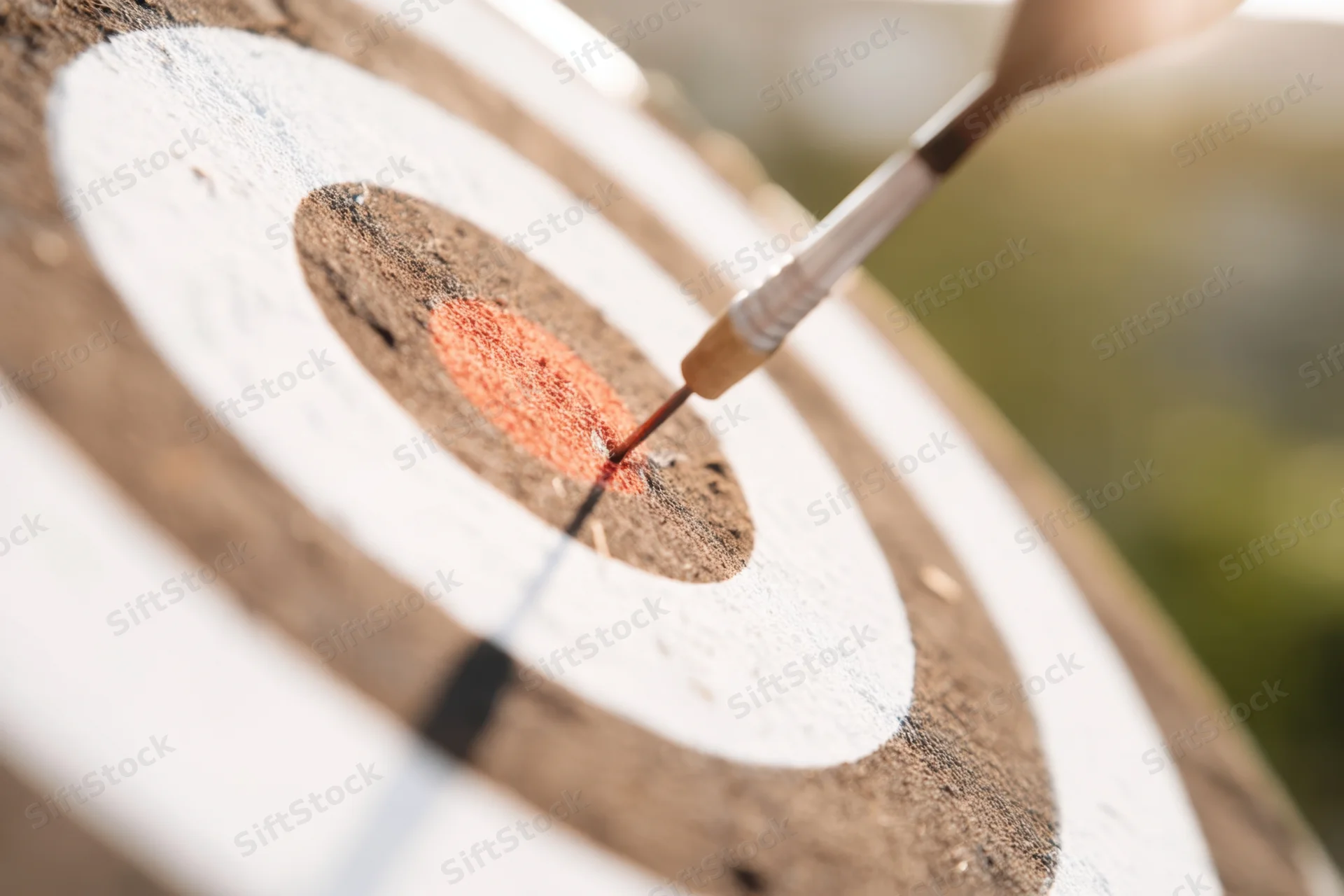 Dart hitting the bullseye of a wooden dartboard in close-up view