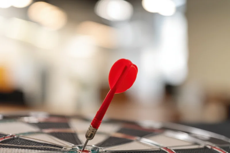 Red heart-shaped dart landed in center of dartboard indoors