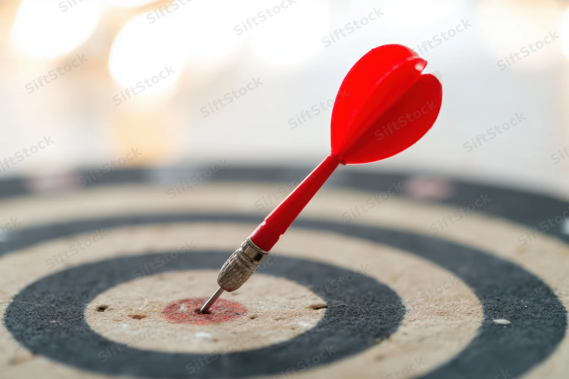 Red heart-shaped dart hitting the bullseye of a dartboard