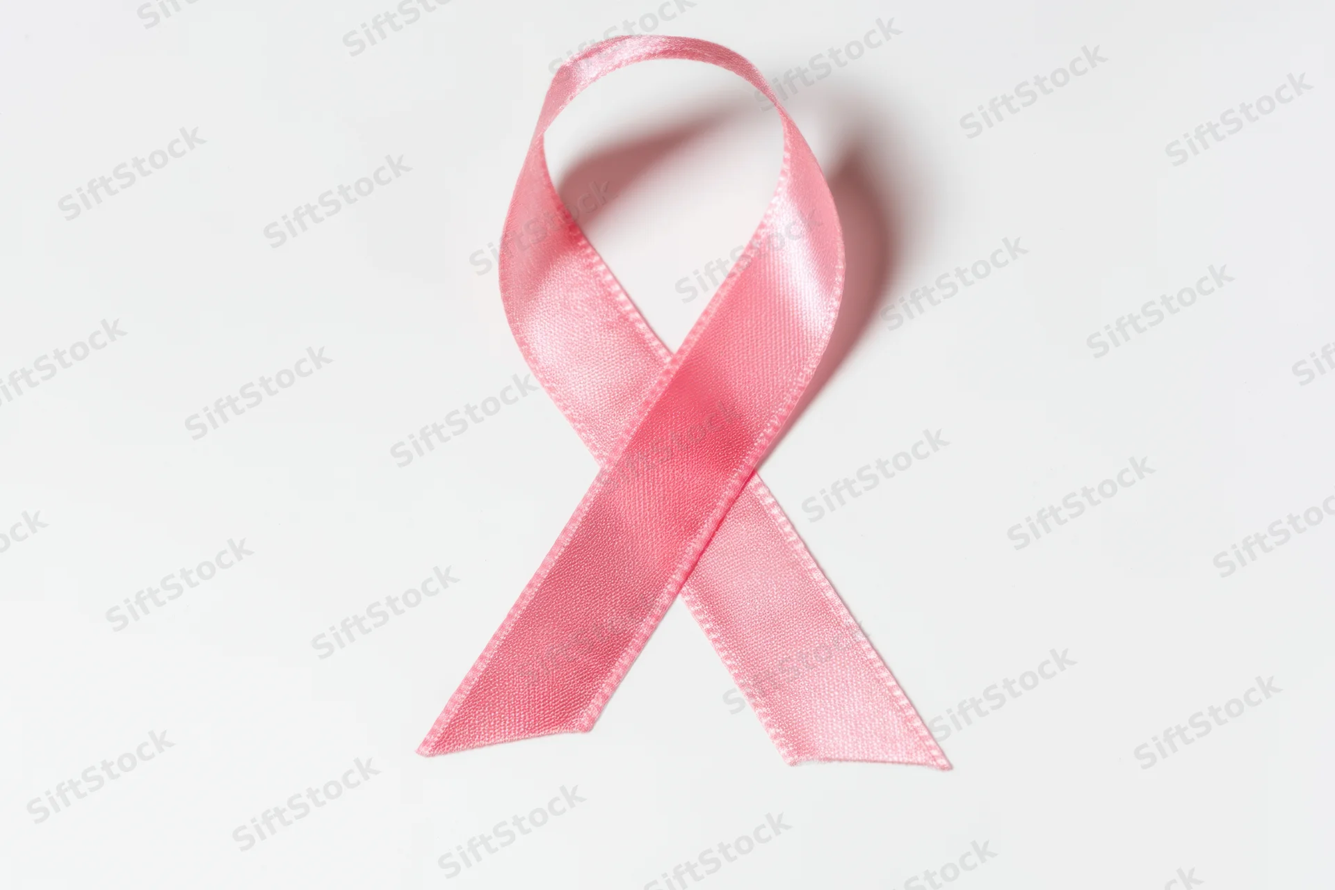 Pink ribbon arranged in loop shape on white background