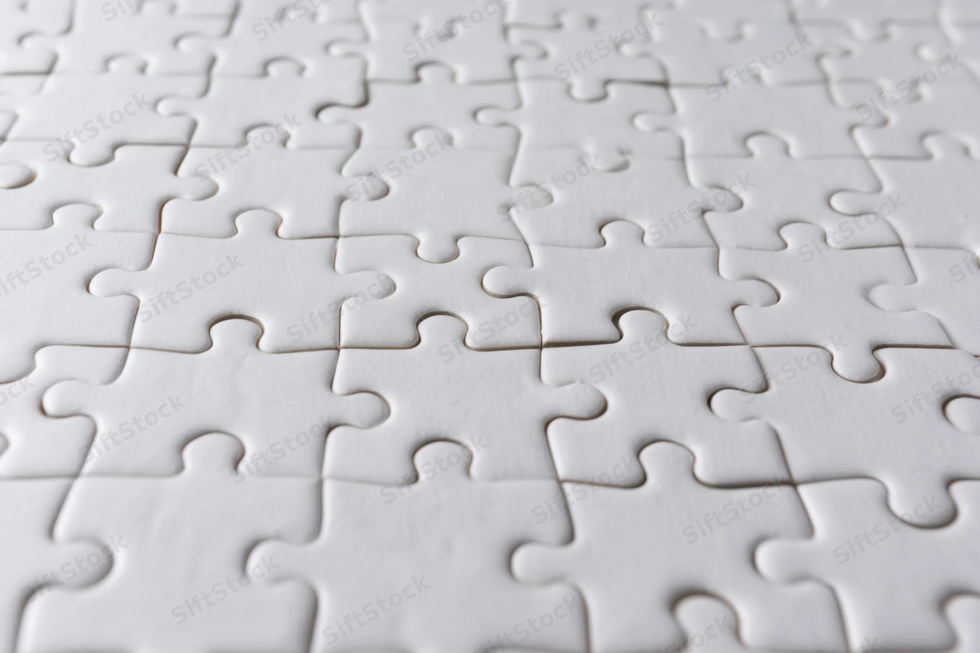 White interlocking puzzle pieces arranged flat on a smooth surface