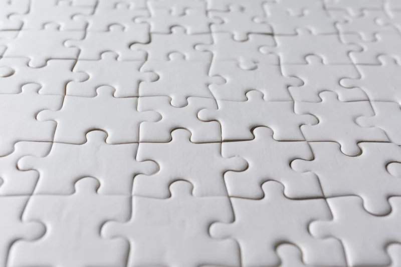 White interlocking puzzle pieces arranged flat on a smooth surface