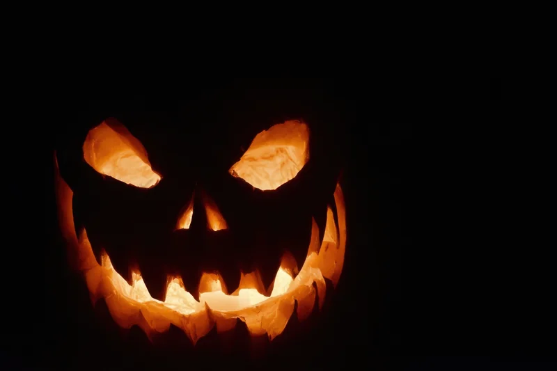 Glowing carved pumpkin with jagged grin against black background