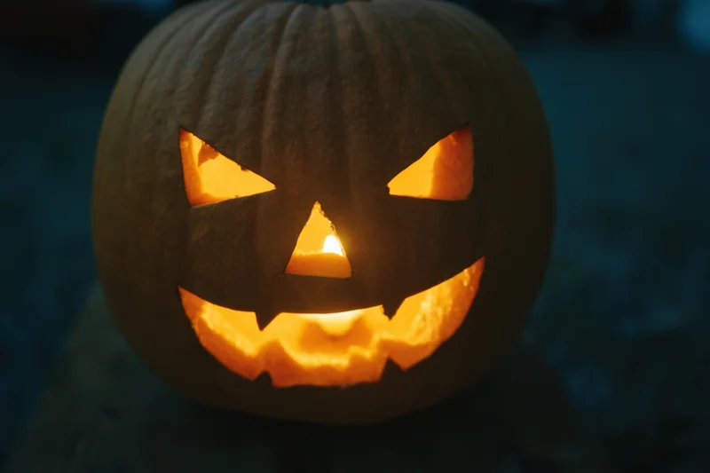 Glowing jack-o-lantern with carved menacing grin lit from within at night