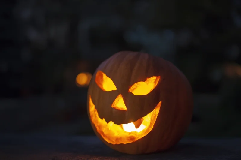 Glowing jack-o-lantern with carved menacing grin outdoors at night