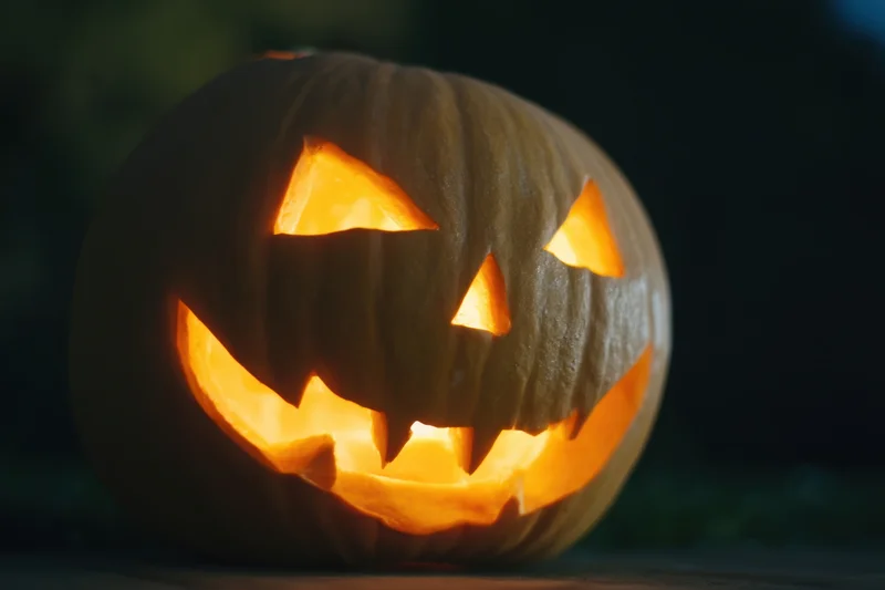 Glowing jack-o-lantern with carved menacing grin lit from within at night