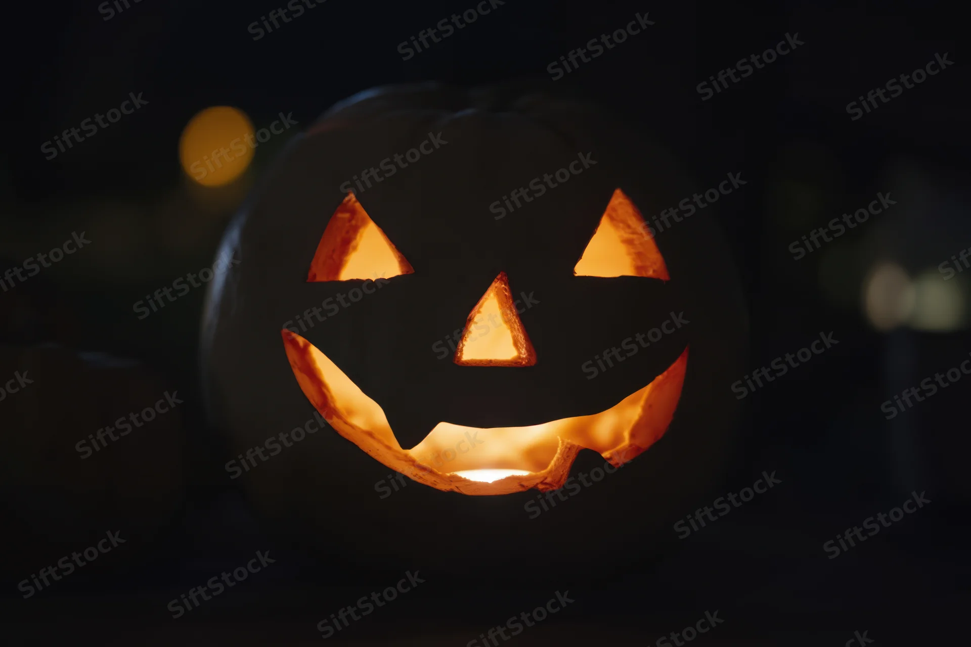 Glowing jack-o-lantern with carved mischievous face in dark night setting