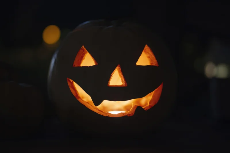 Glowing jack-o-lantern with carved mischievous face in dark night setting