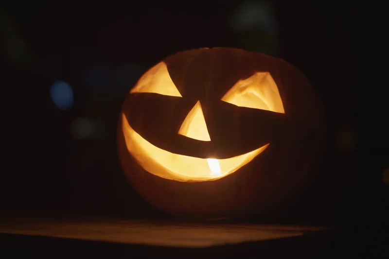 Glowing jack-o-lantern with mischievous carved face in dark setting