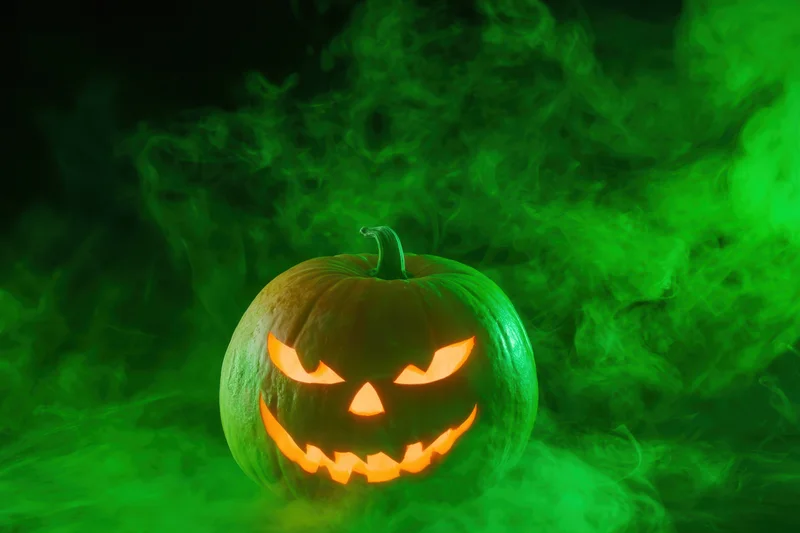 Glowing jack-o-lantern with carved face surrounded by green smoke