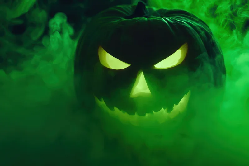 Glowing jack-o-lantern with carved mischievous face in green smoke at night