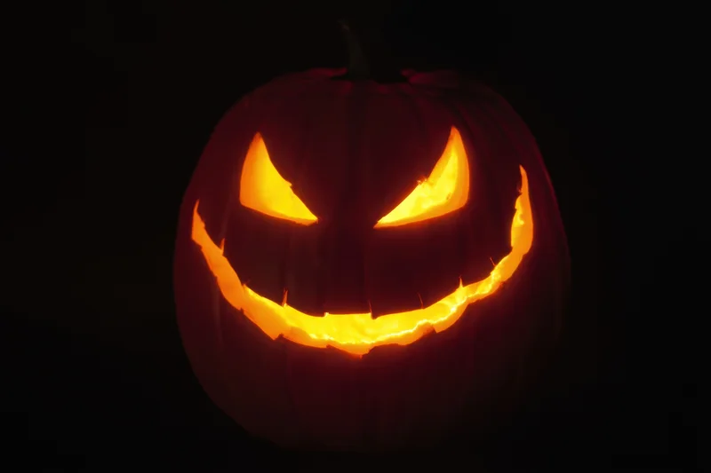 Glowing jack-o-lantern with carved mischievous grin in dark background