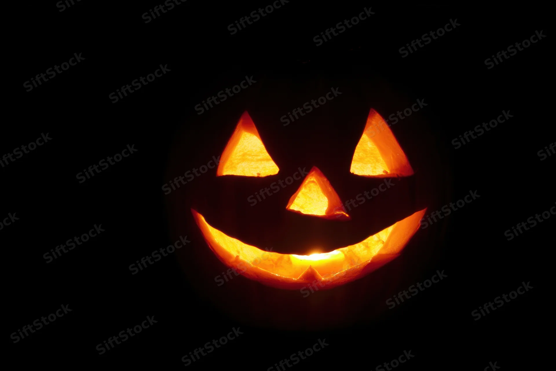 Glowing jack-o-lantern with carved face and mischievous grin in dark night