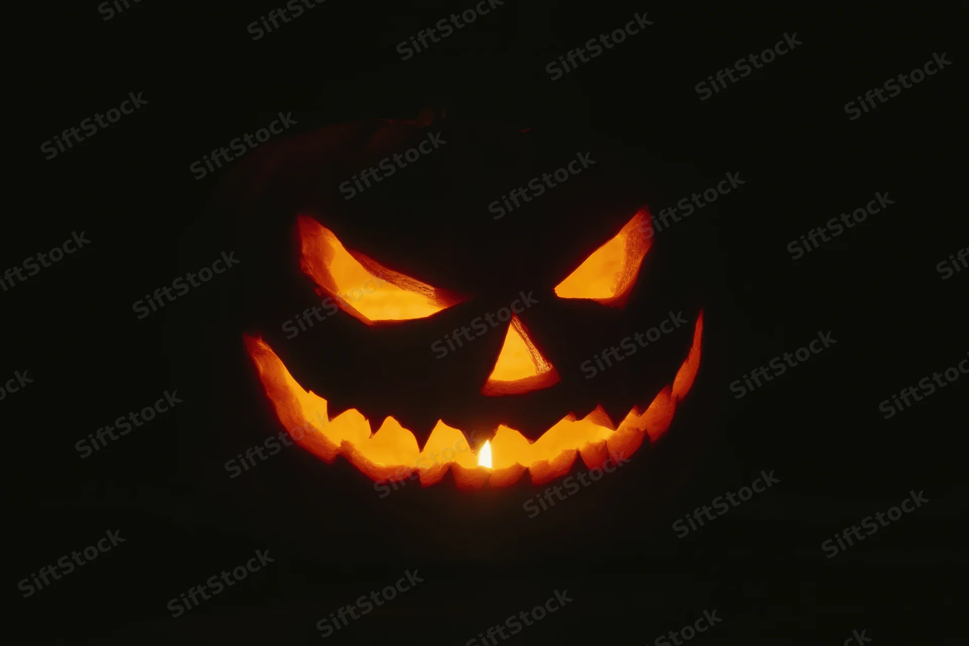 Glowing jack-o-lantern with carved mischievous grin in dark night