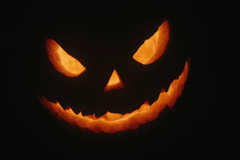 Glowing jack-o-lantern with carved face and eerie grin in darkness