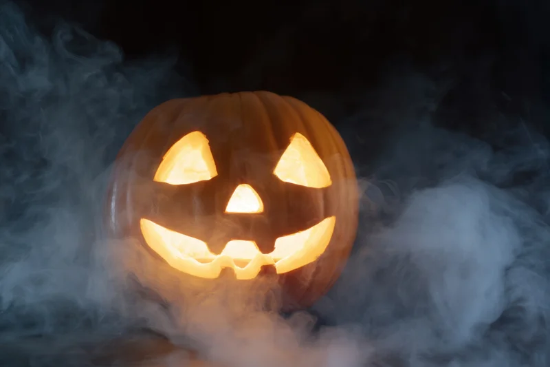 Glowing jack-o-lantern with carved face surrounded by smoke at night