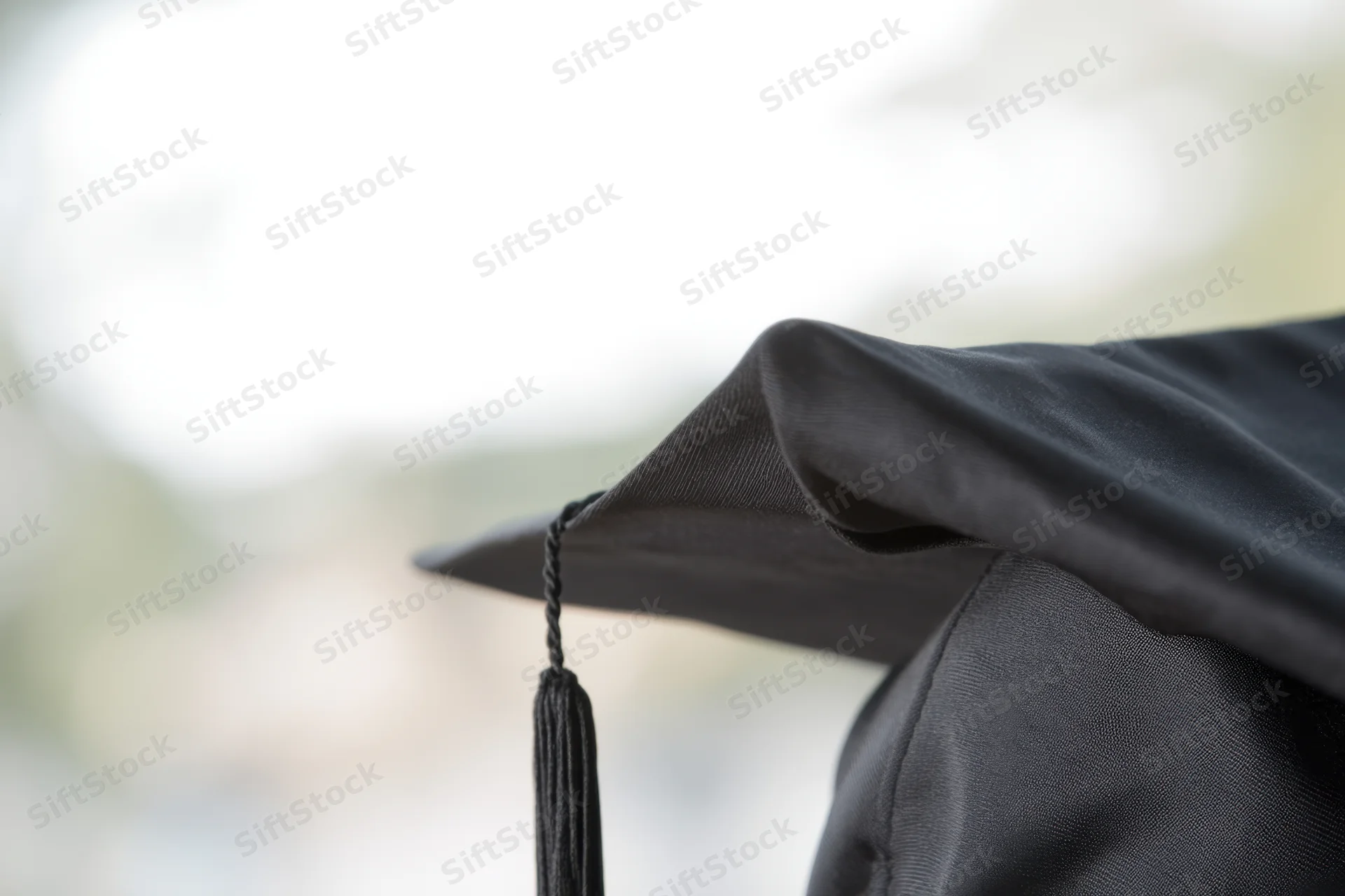 Close-up of a black graduation cap with tassel against a softly blurred outdoor background