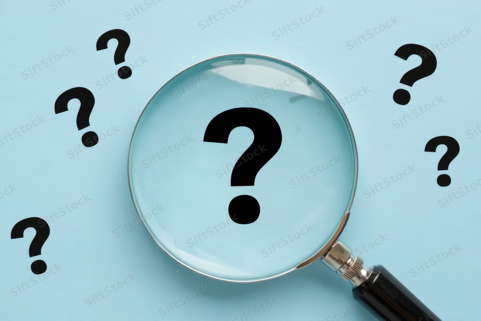 Magnifying glass focusing on a large question mark surrounded by smaller question marks on a light blue background