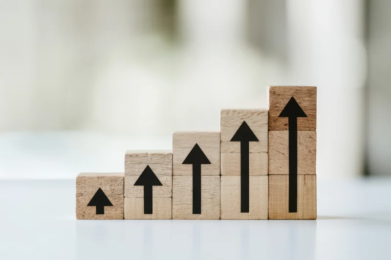 Wooden blocks stacked in ascending order with black arrows pointing upward on a white surface