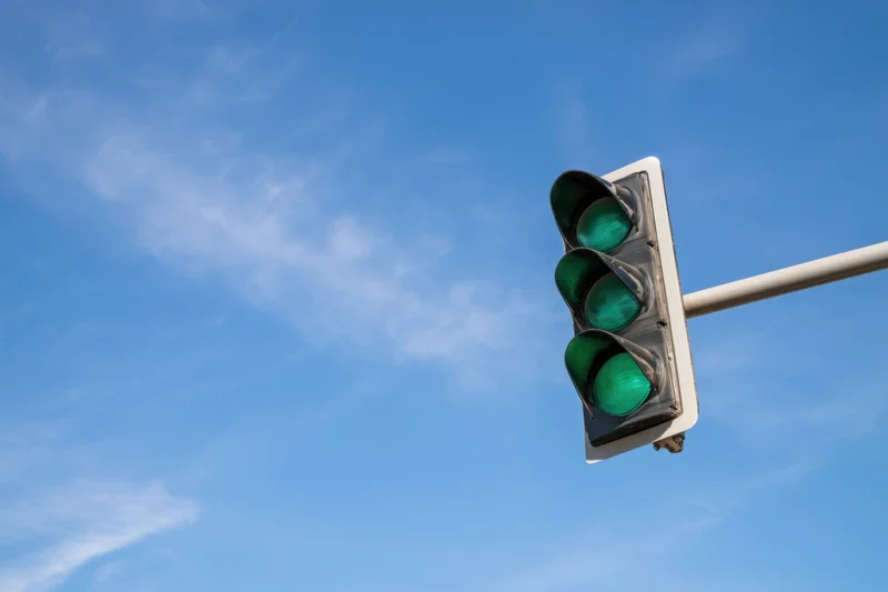 Modern traffic light with three green signals against a clear blue sky