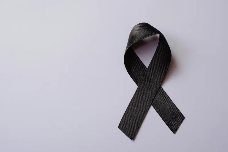 Black awareness ribbon neatly arranged on soft gray surface
