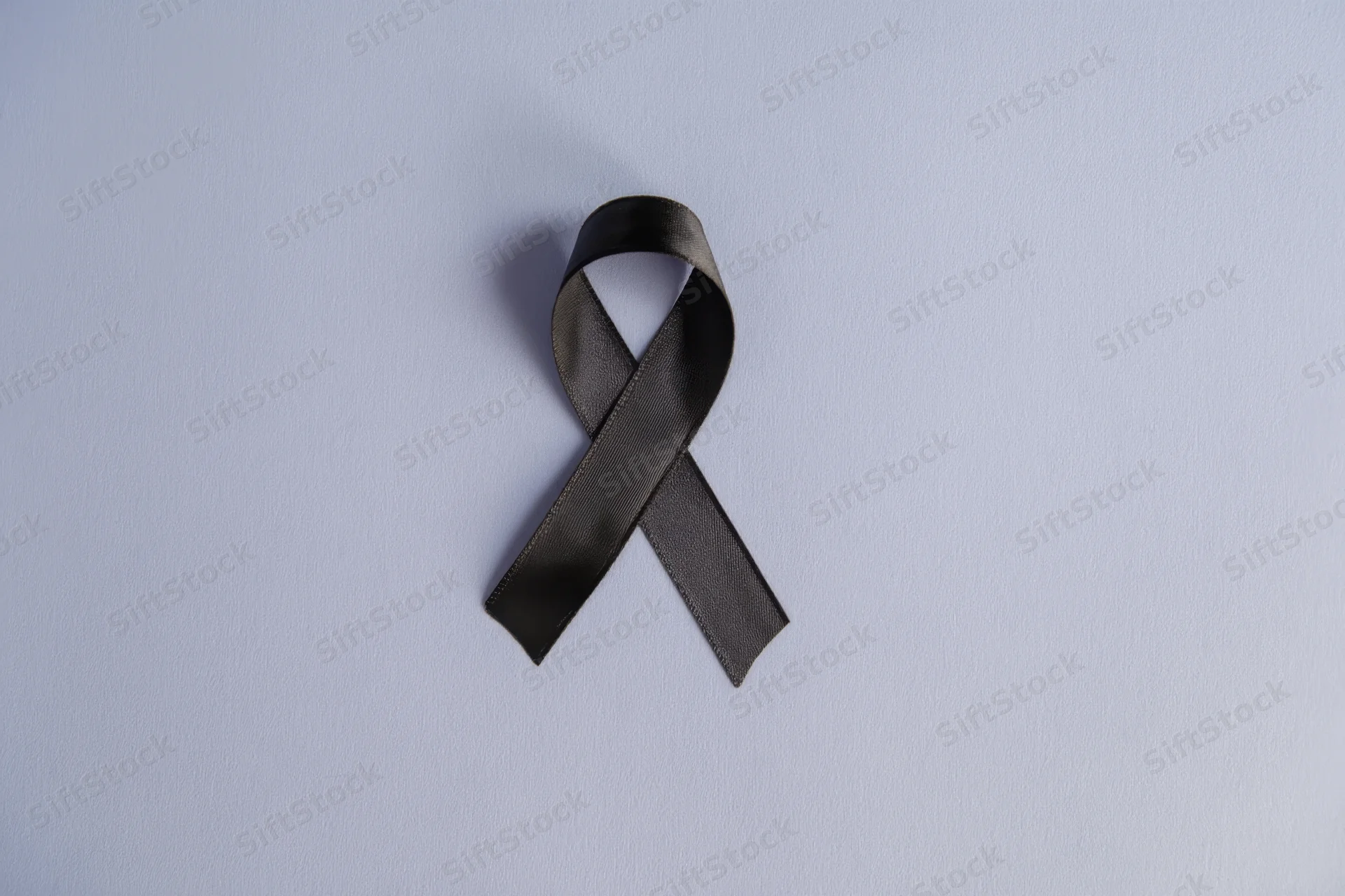 Black awareness ribbon neatly arranged on soft gray background