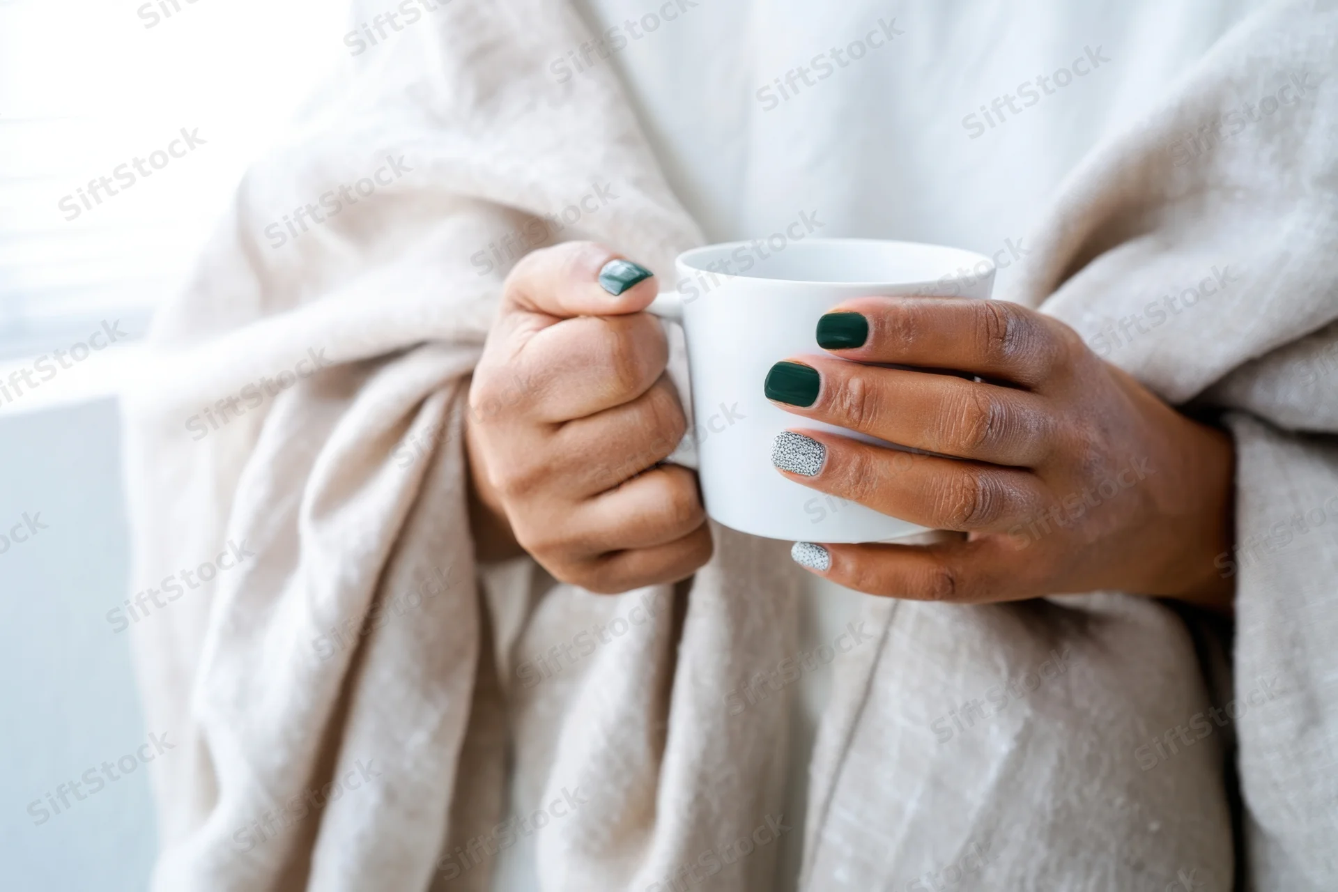 Woman holding white cup wrapped in soft blanket