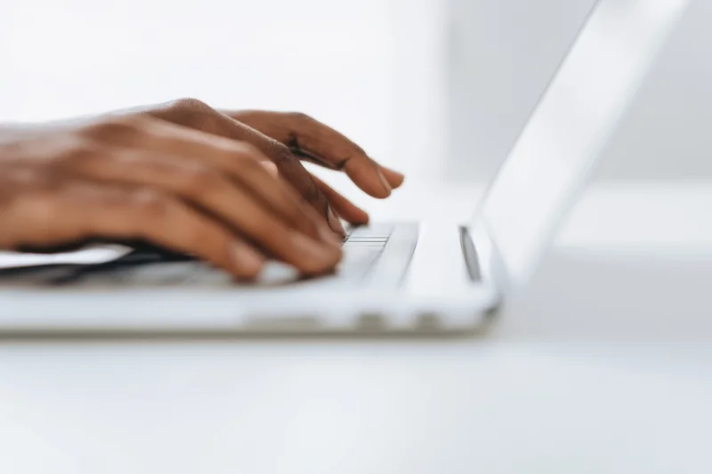 Hands typing on a sleek white laptop at a modern desk