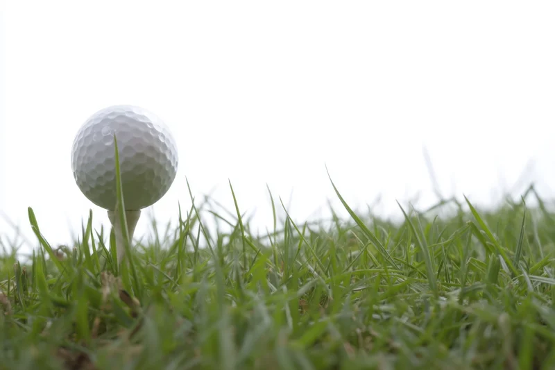 Golf ball on a tee in vibrant green grass with copyspace above