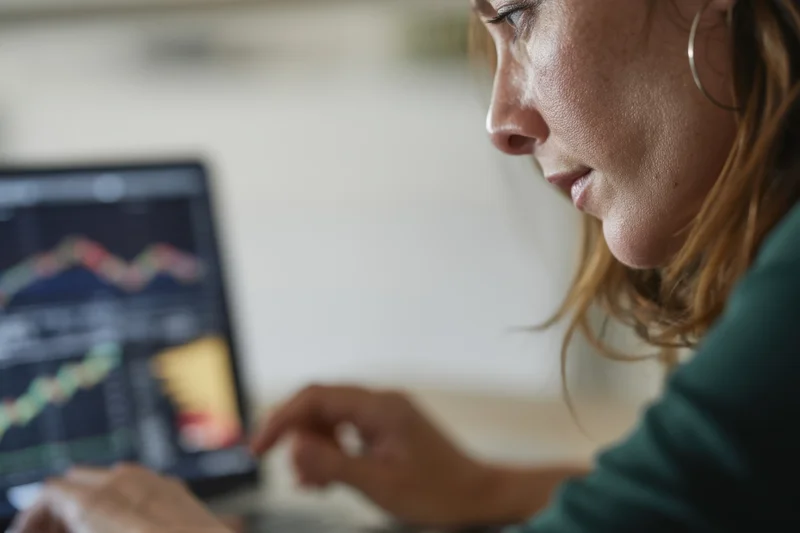 Woman analyzing financial data on laptop screen in office setting
