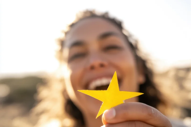 Woman laughing while holding a yellow star-shaped object outdoors in sunlight