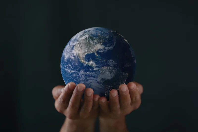 Hands holding a glowing blue Earth globe against dark background