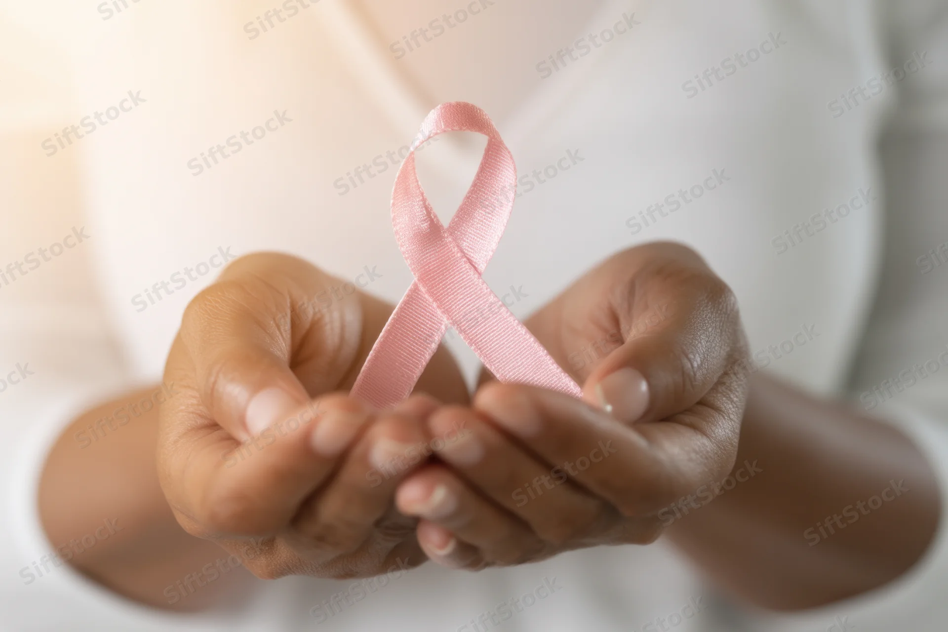 Woman holding pink ribbon in cupped hands