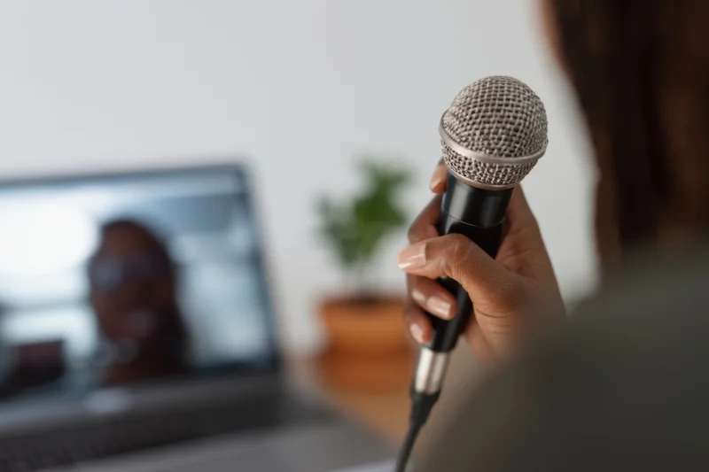 Woman holding microphone for podcast recording in home office setting