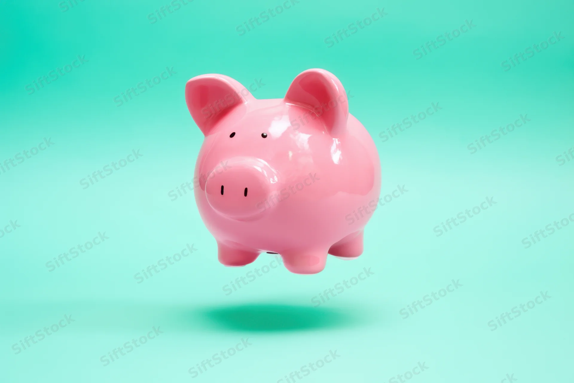 Pink ceramic piggy bank floating against a soft green gradient background