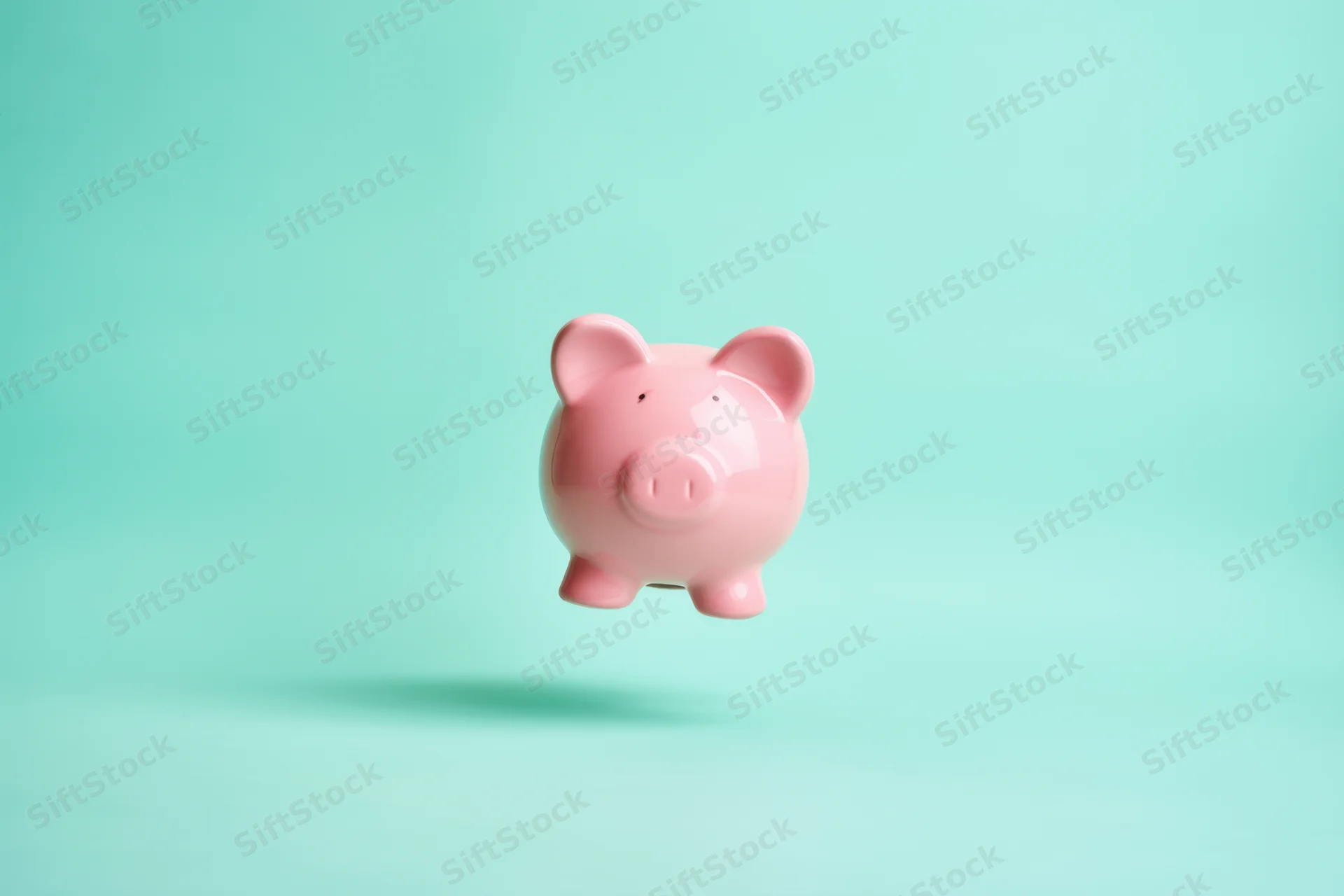 Pink piggy bank floating against a soft turquoise gradient background