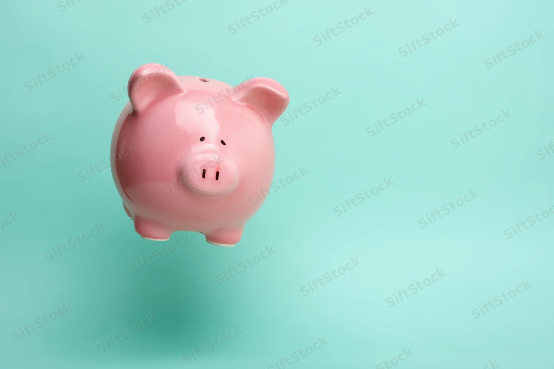 Pink ceramic piggy bank floating against a soft turquoise gradient background
