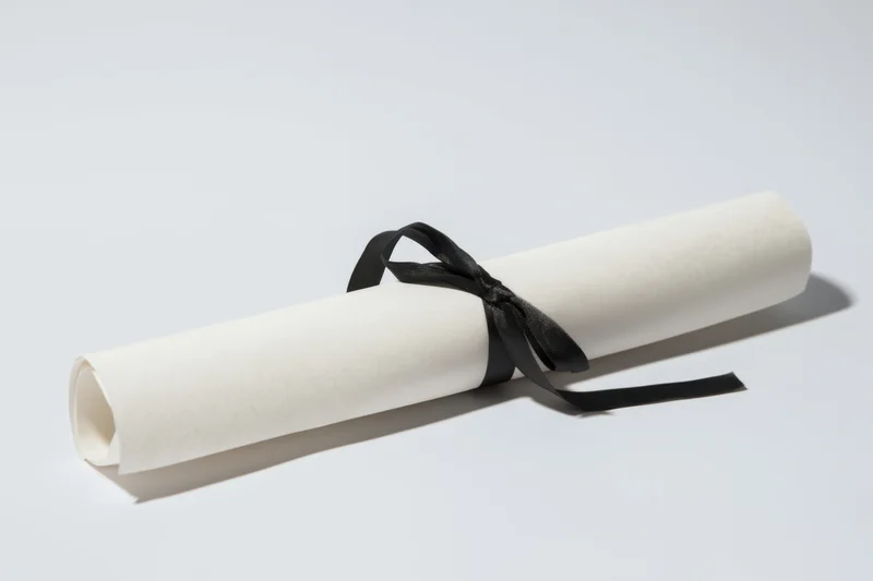 Rolled diploma secured with black ribbon on white background