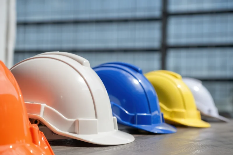 Row of colorful construction hardhats arranged on a table indoors